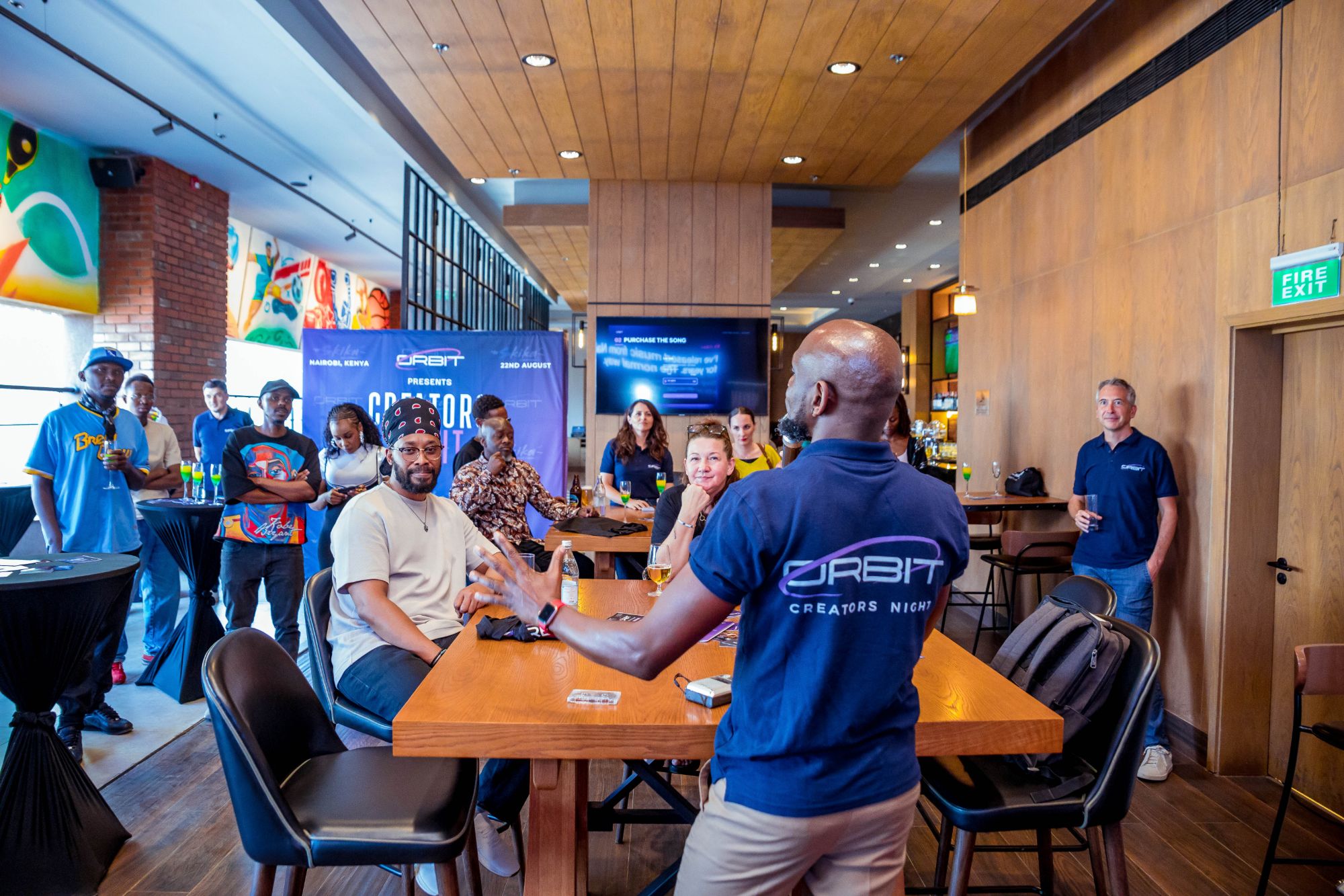 The Nairobi room mid-demo — Orbit staff at the table, the Creators Night banner behind them, and the purchase screen on the wall