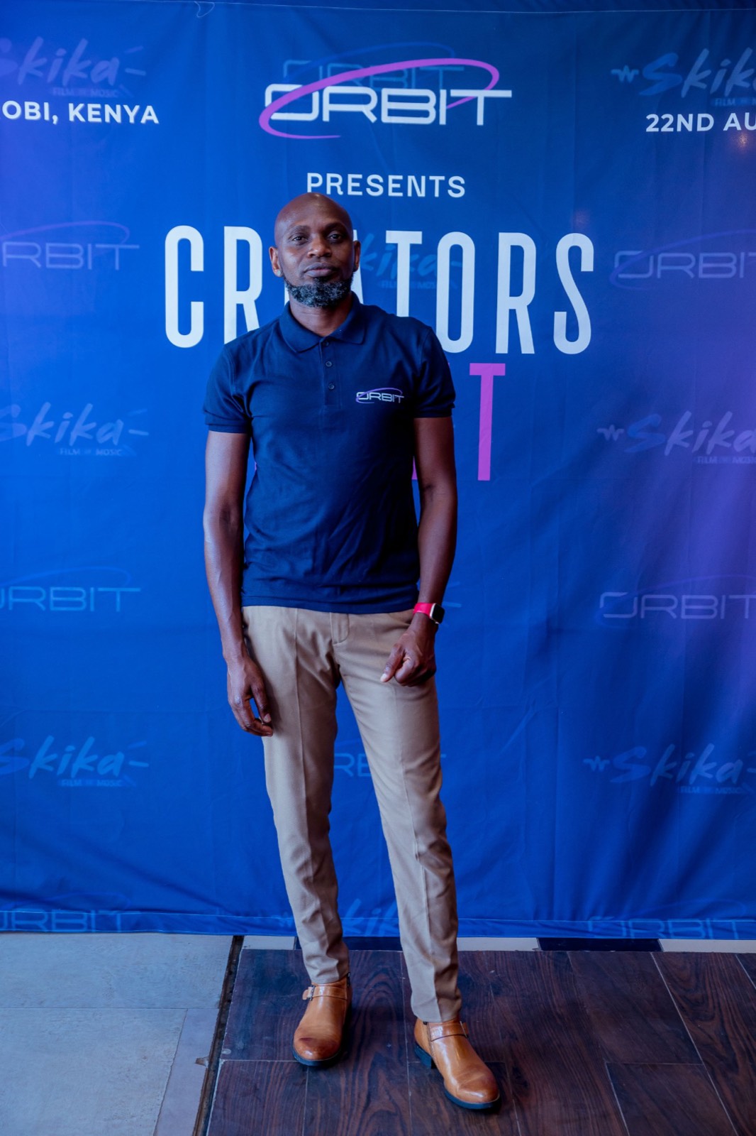 Moses Sospeter (theSOS) in an Orbit polo, standing in front of the Creators Night backdrop