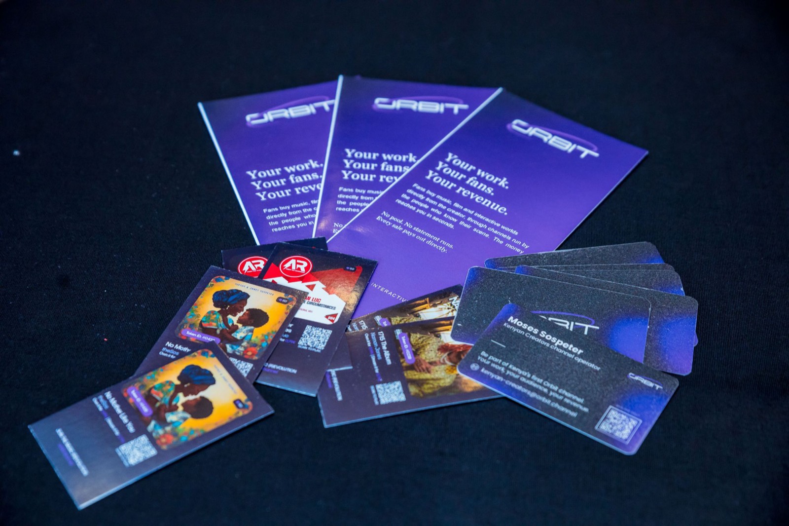 Orbit flyers and collectible release cards fanned out on a black cloth