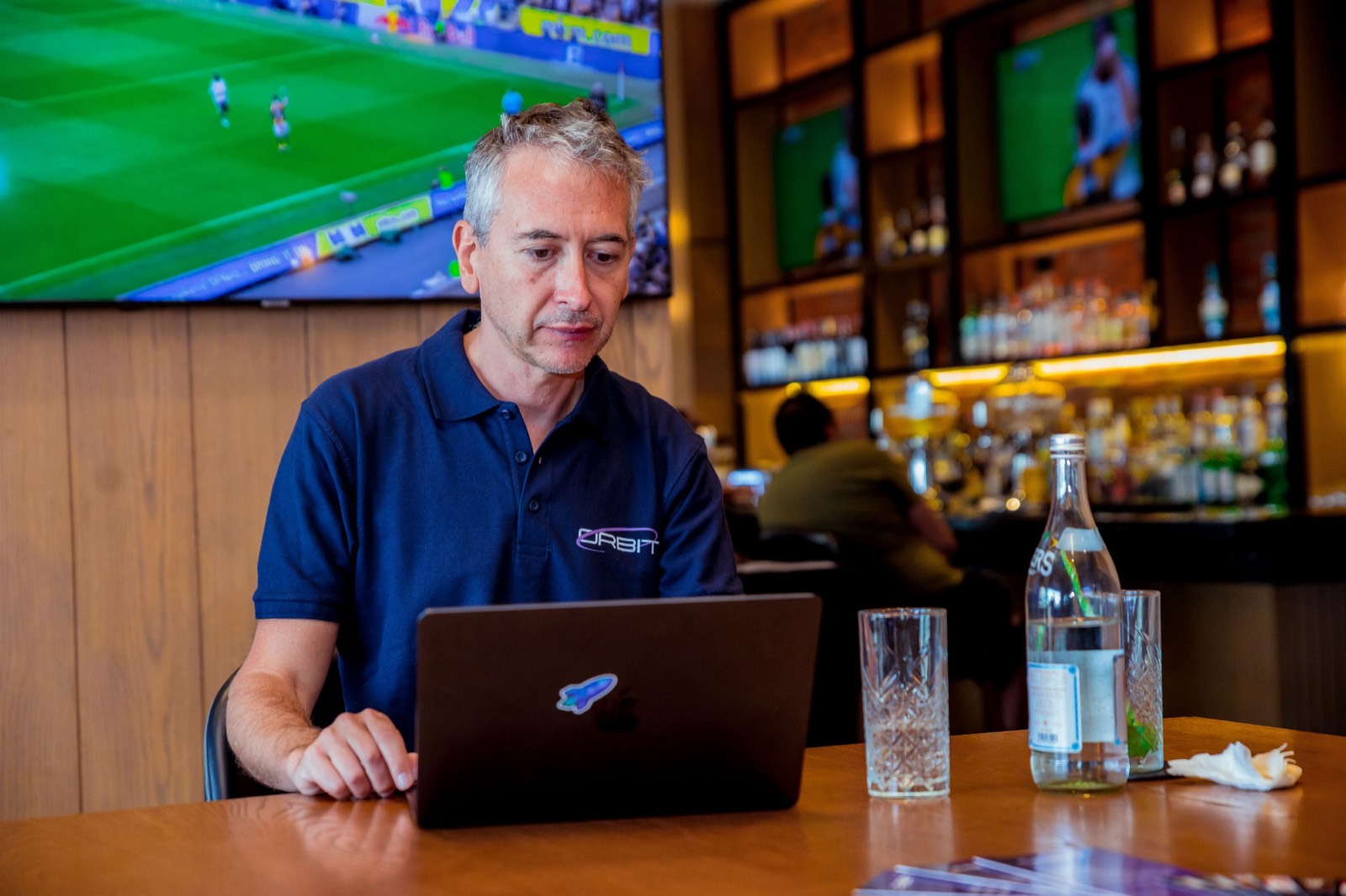 A member of the Orbit team working on a laptop at the bar before the program starts